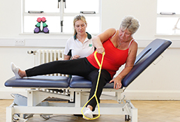Liverpool OT patient uses resistance band to stretch leg during therapy.