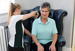 Liverpool OT therapist shows patient how to adjust her posture while seated.