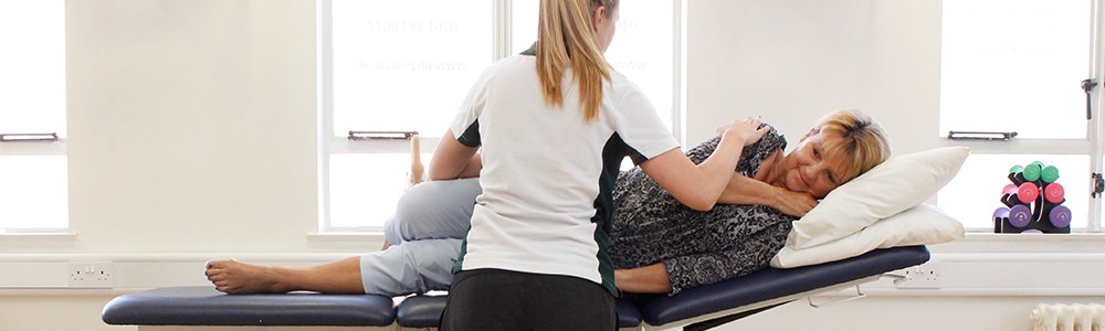 Liverpool OT patient lies down during therapy while Liverpool OT therapist aids her.