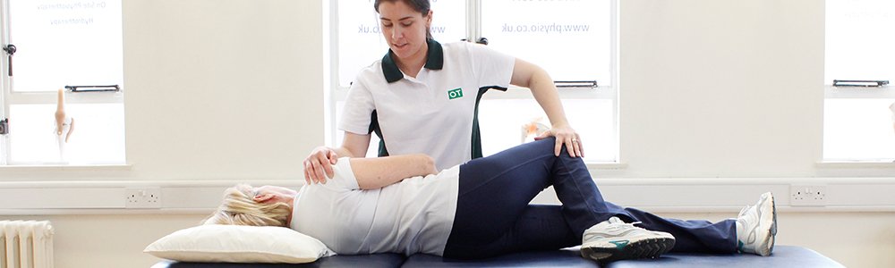 Liverpool OT trained therapist aids patient with stretches on therapist bench