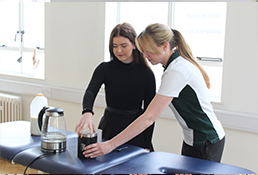 Liverpool OT therapist aids young patient in making a cup of coffee.